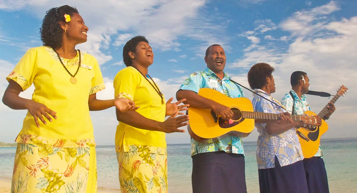 Castaway Island Fiji team members singing with guitars beside the beach