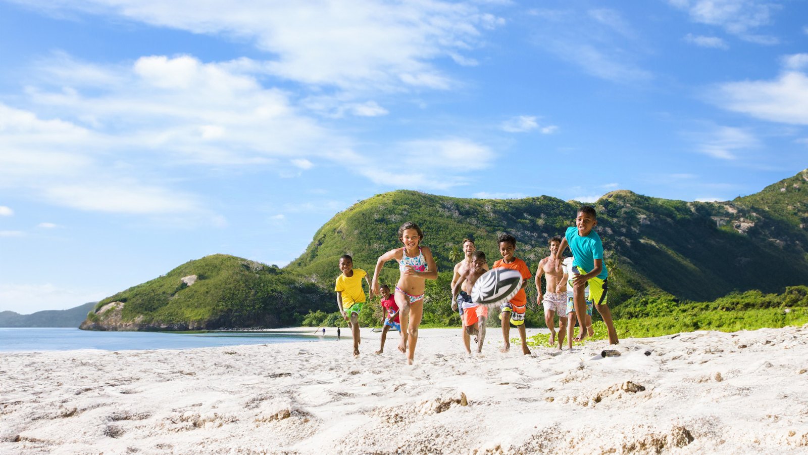Children and adults playing rugby on a Fiji beach