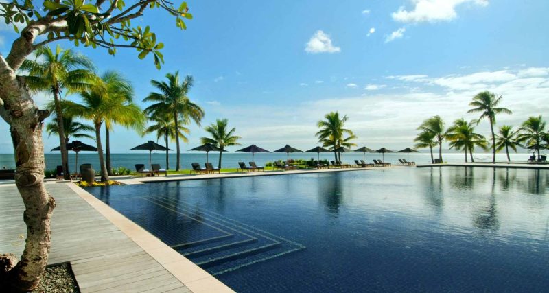 Palm-fringed resort pool overlooking the sea at Hilton Fiji Beach Resort & Spa