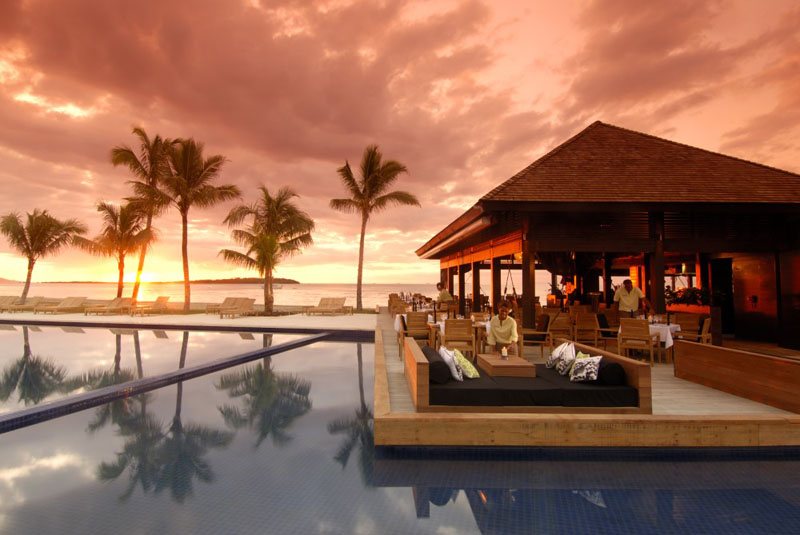 Sunset dining beside a resort pool at Hilton Fiji