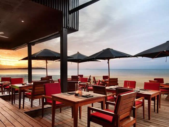 Beachfront restaurant tables at sunset at Hilton Fiji