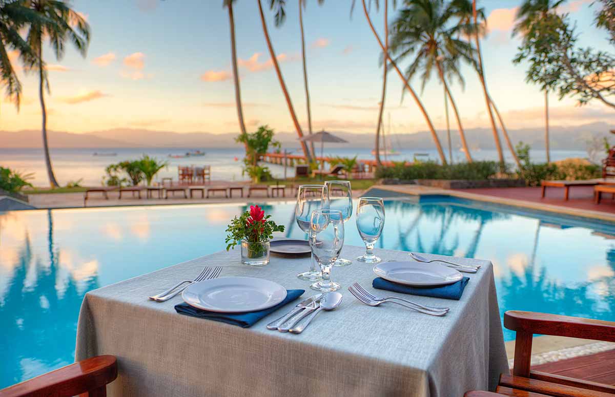 Table overlooking the pool and Savusavu Bay at sunset at Jean-Michel Cousteau Resort