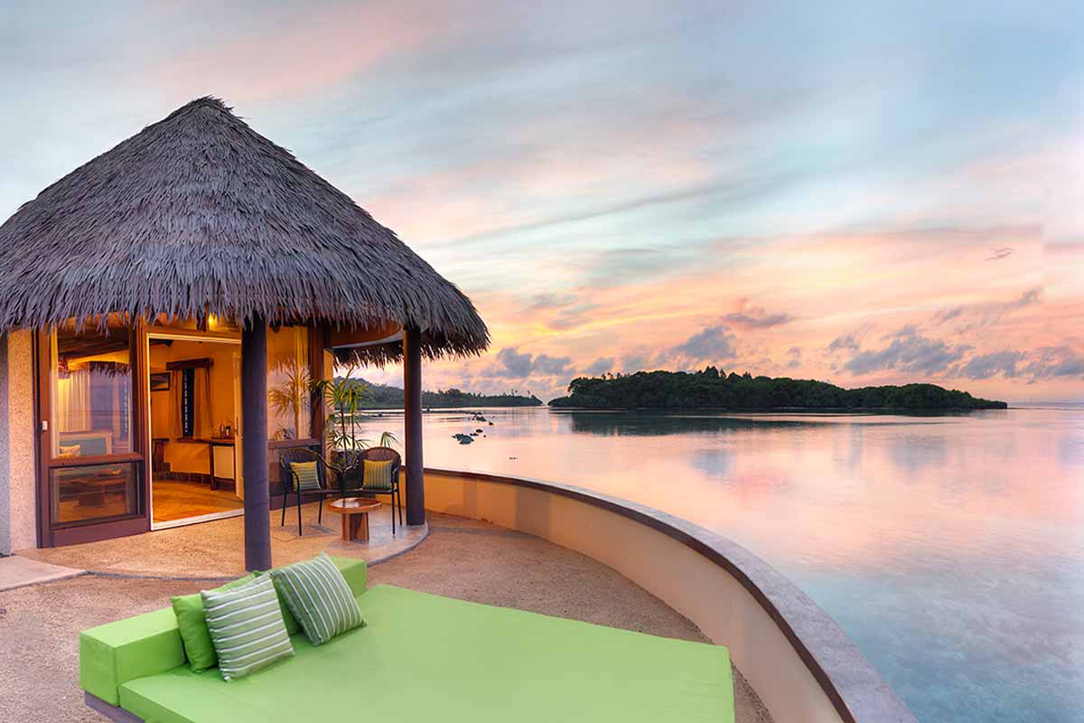 Thatched waterfront bure and circular terrace at sunset at Koro Sun Resort
