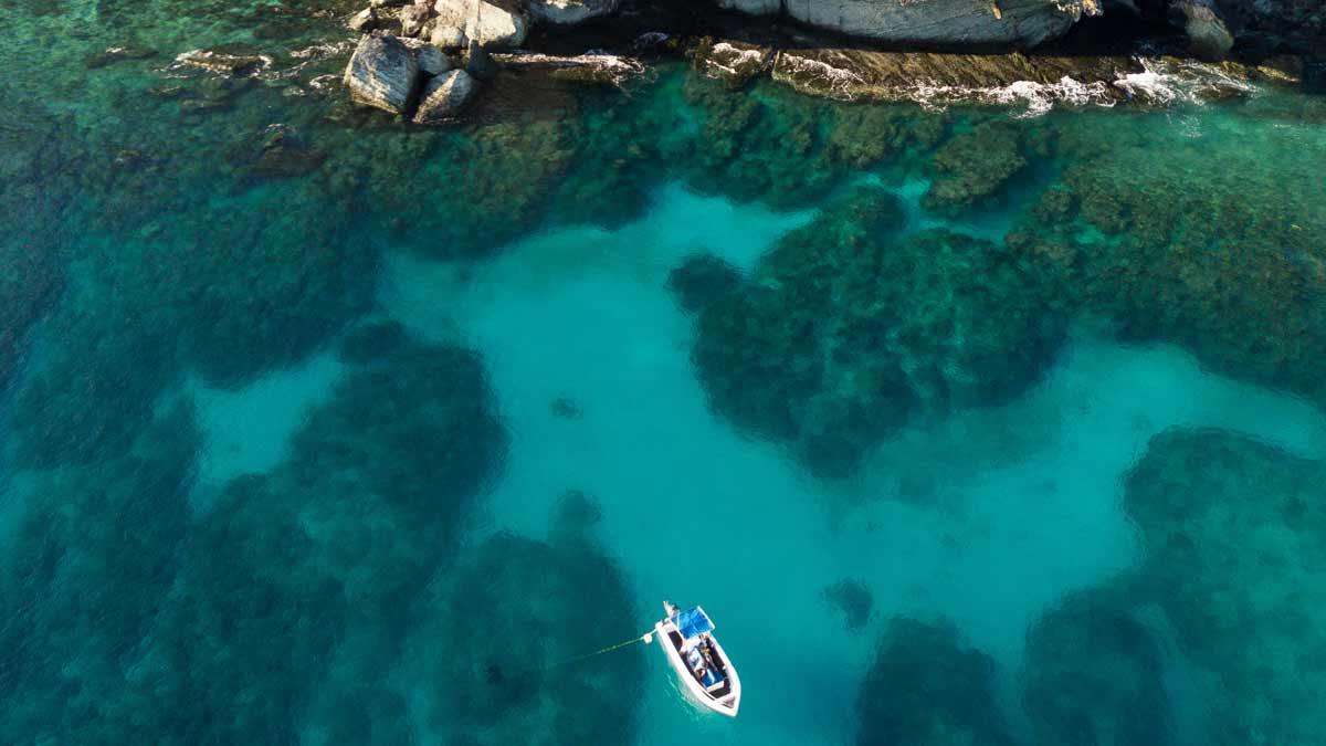 Small boat on clear blue water beside a rocky coastline near Likuliku Lagoon Resort
