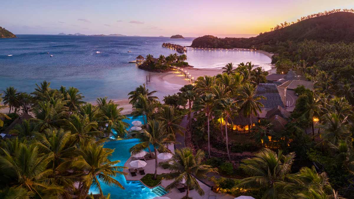 Sunset over the pool, gardens and lagoon at Likuliku Lagoon Resort