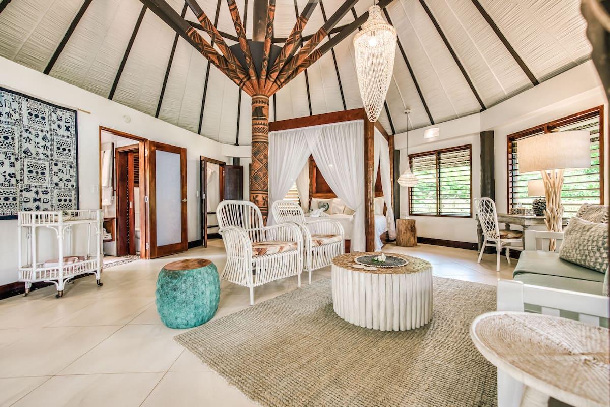 Four-poster bed and sitting area inside a Matangi Oceanview Bure