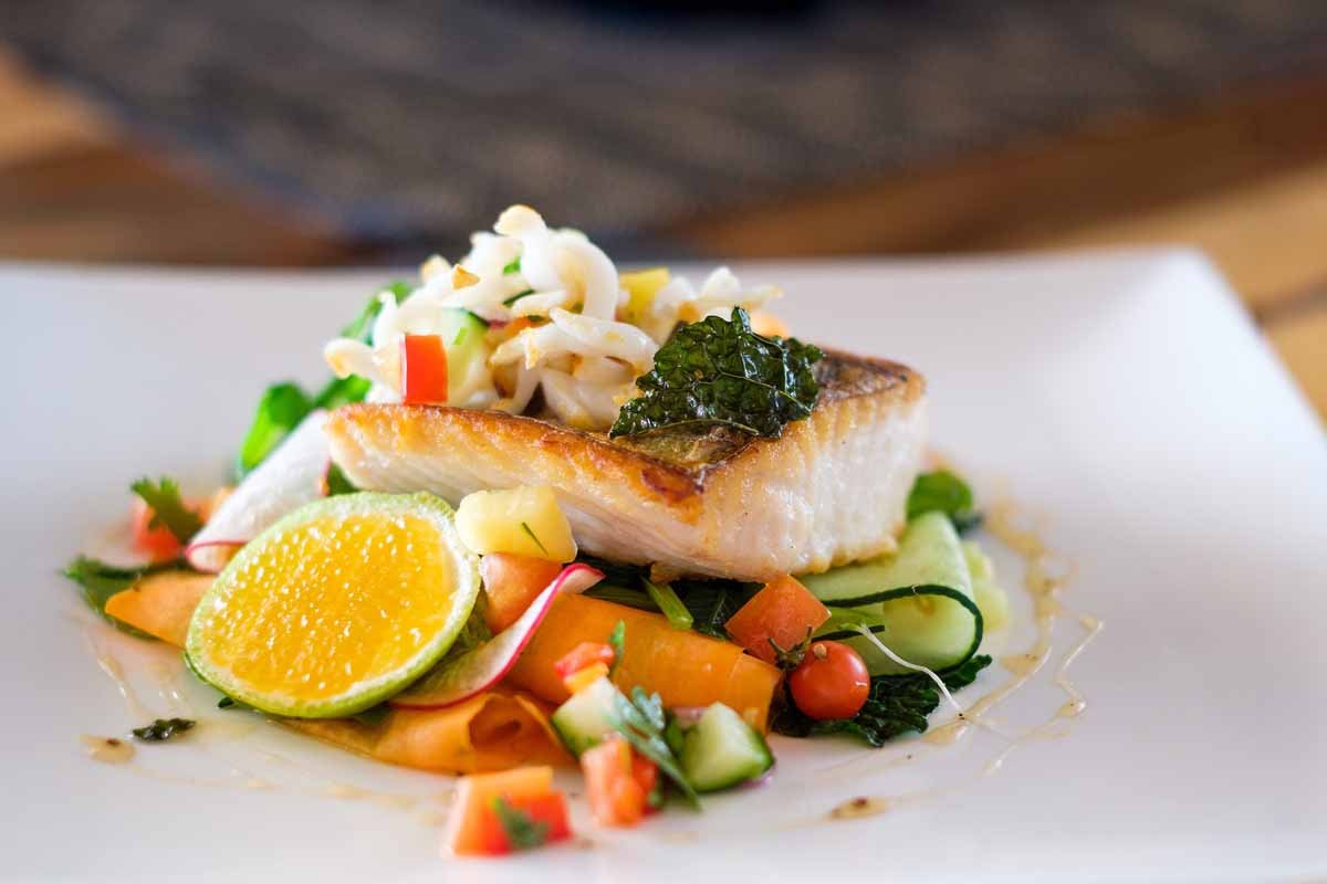 A plated fish dish with vegetables and lime at Musket Cove Island Resort