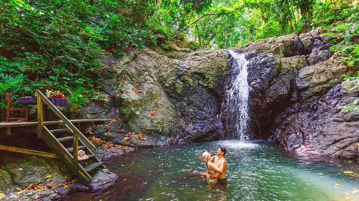 Guests beside a rainforest waterfall at Namale Resort