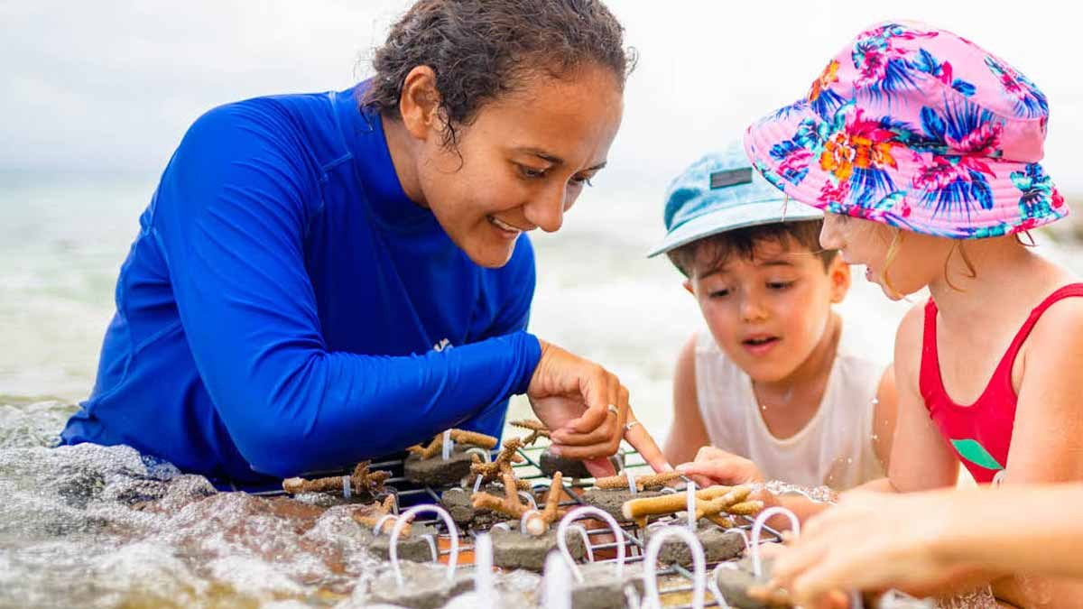 Nanuku Resort Fiji team member sharing a hands-on activity with two children