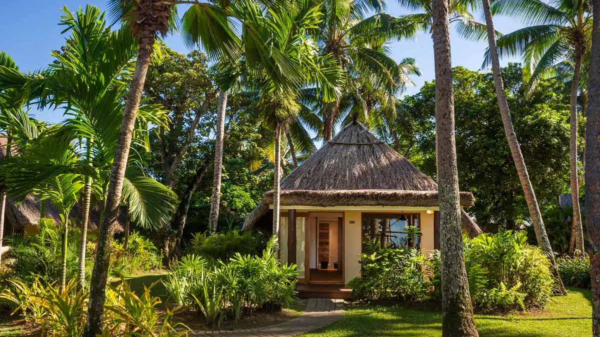 Traditional bure among palms at Outrigger Fiji Beach Resort