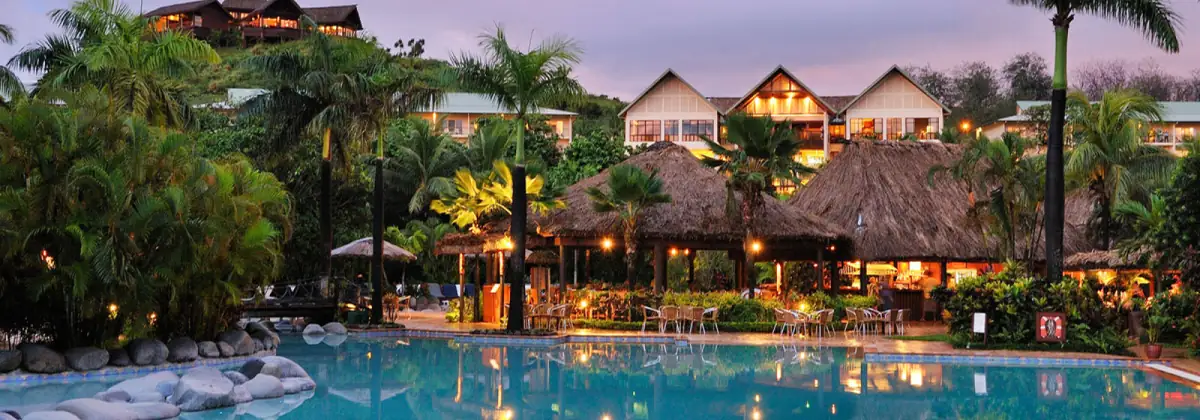 Pool and restaurant at dusk at Outrigger Fiji Beach Resort