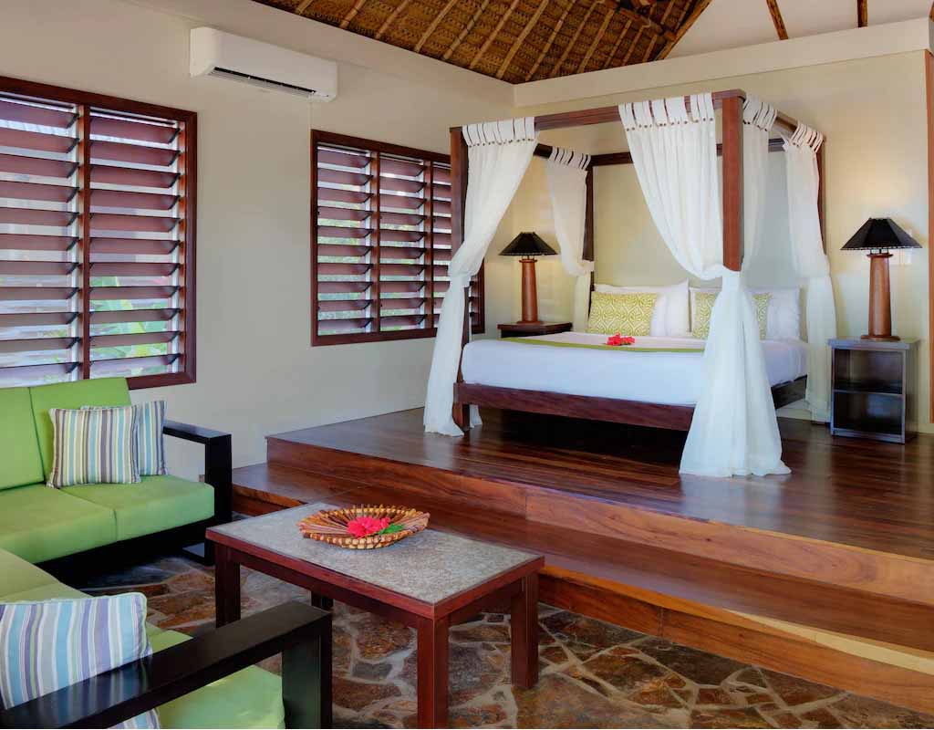 Four-poster bed and living area in a One Bedroom Beachfront Villa at Paradise Cove Resort