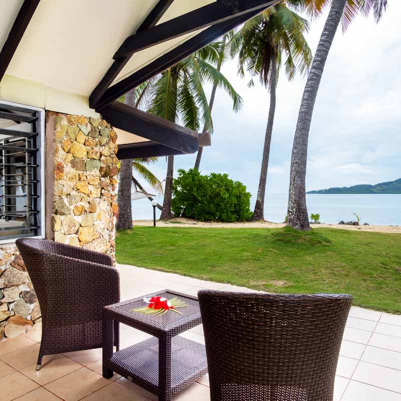 Beachfront Bure patio overlooking the lawn and lagoon at Plantation Island Resort