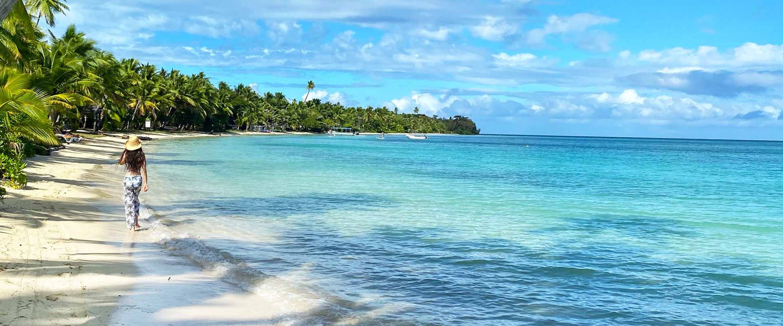 Palm-lined beach and clear lagoon at Plantation Island Resort