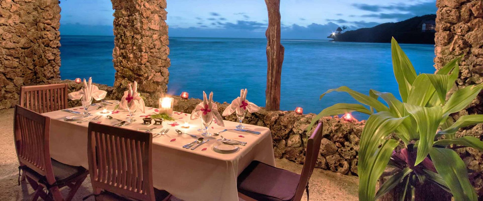 Candlelit dining table beside the sea at Savasi Island Resort