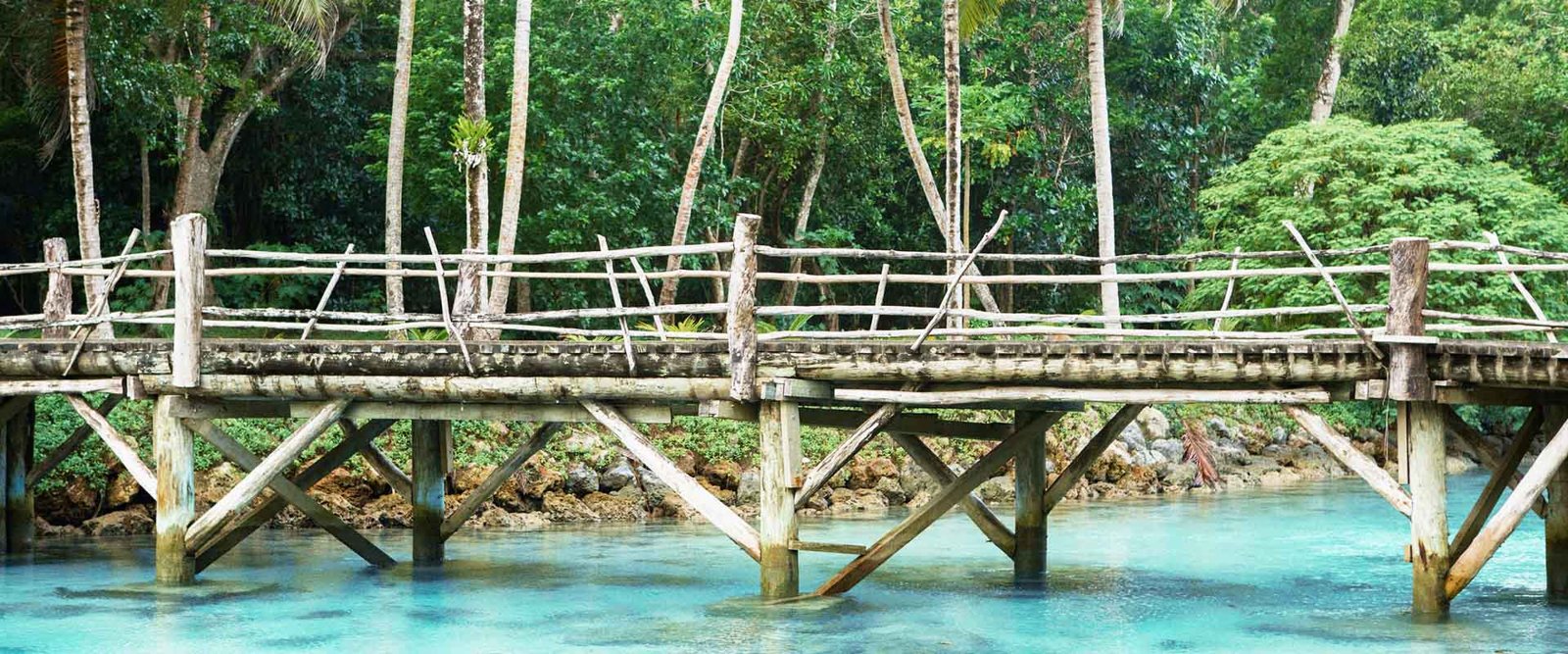Timber footbridge above clear water at Savasi Island Resort