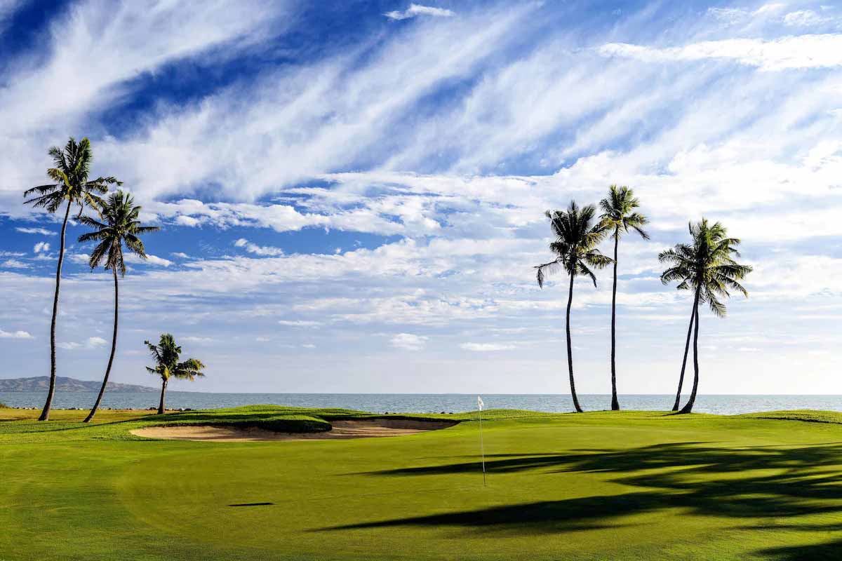 Golf green and palm trees beside the sea at Denarau Golf & Racquet Club
