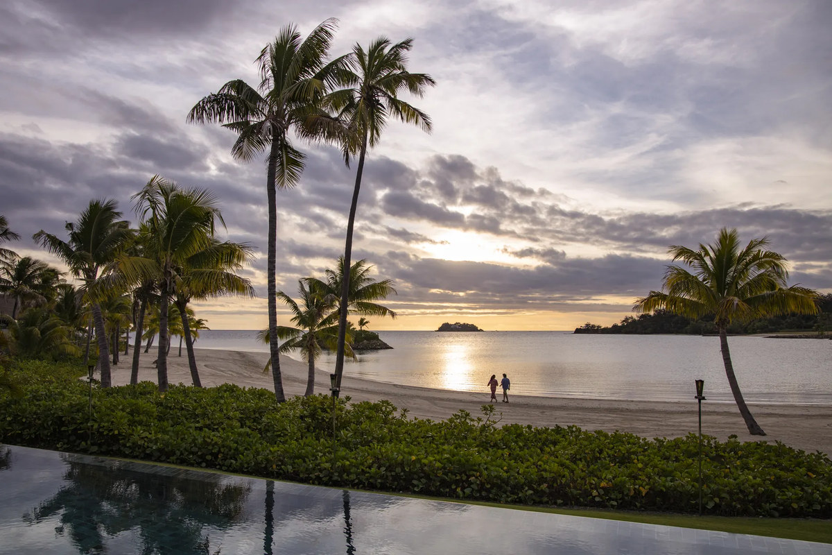 Sunset across a residence pool and the beachfront at Six Senses Fiji