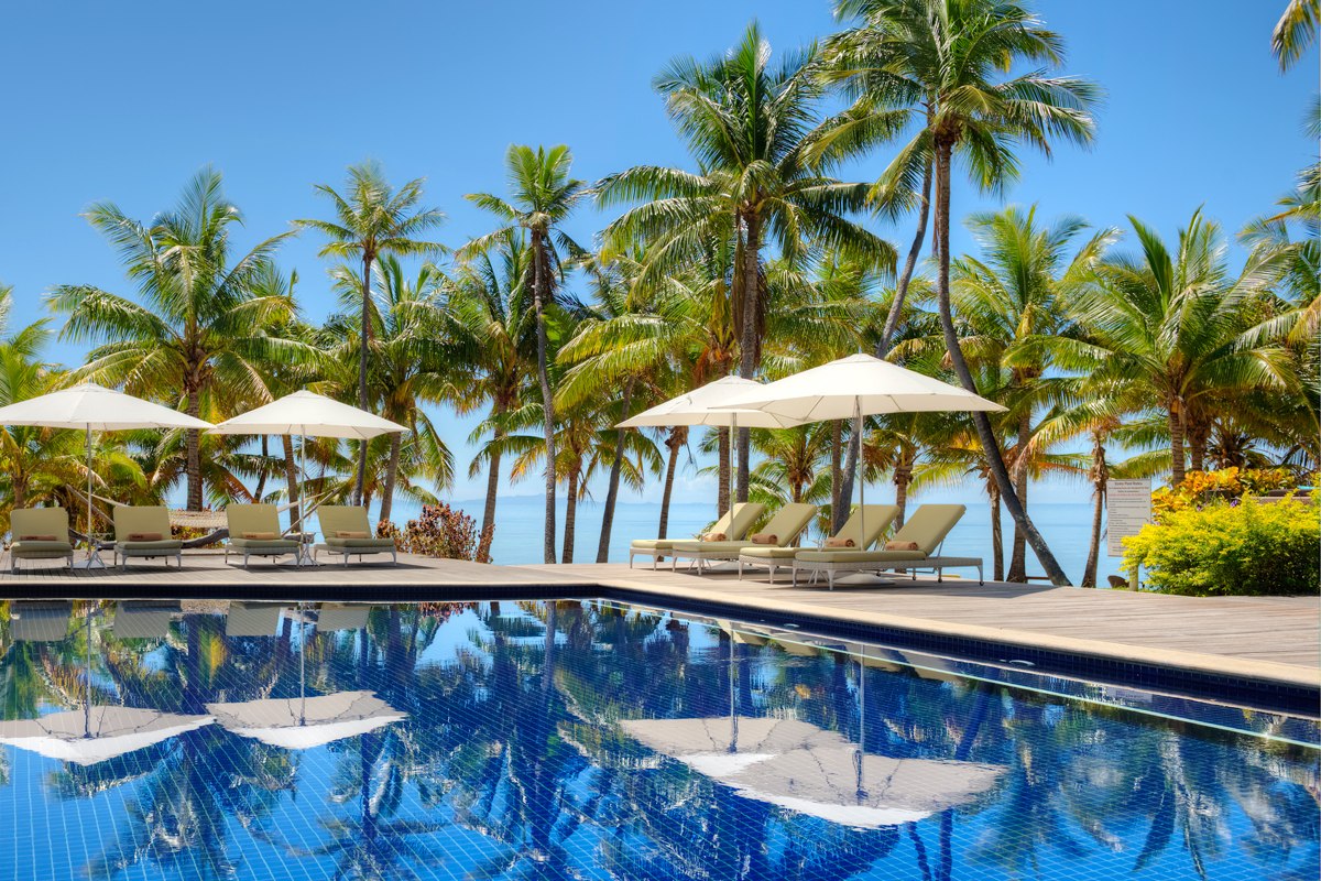 Palm trees and sun umbrellas beside the main pool at VOMO Island Resort