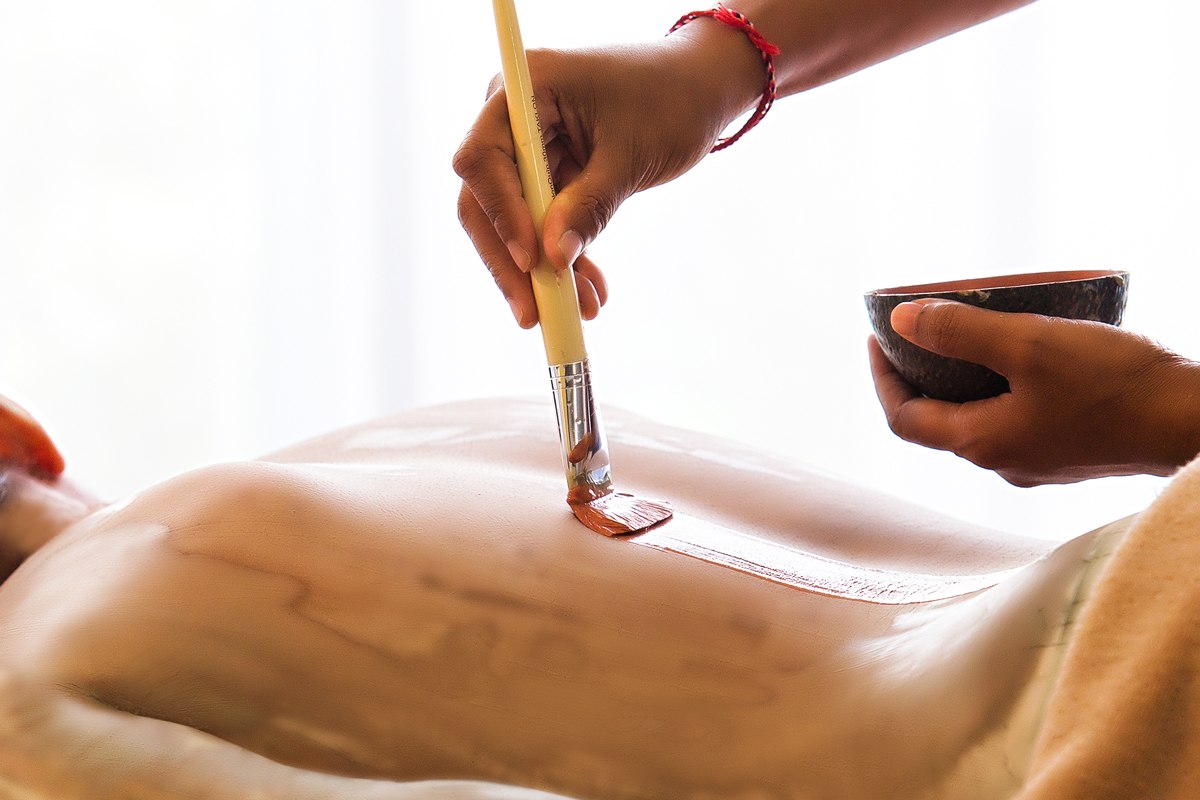 A spa therapist applying a treatment at VOMO Island Resort