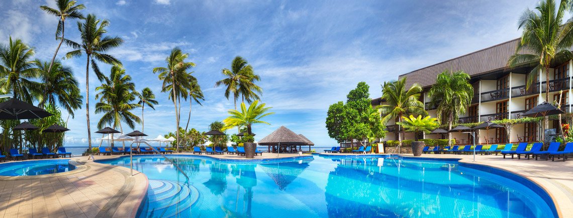 Swimming pool, loungers and beachfront palms at The Warwick Fiji